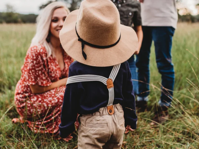 Une famille avec deux enfants dans un champ, l'un des enfants porte un chapeau.