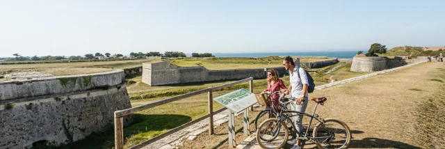 Deux cyclistes s'arrêtent pour lire un panneau d'information sur les fortifications de Saint-Martin.