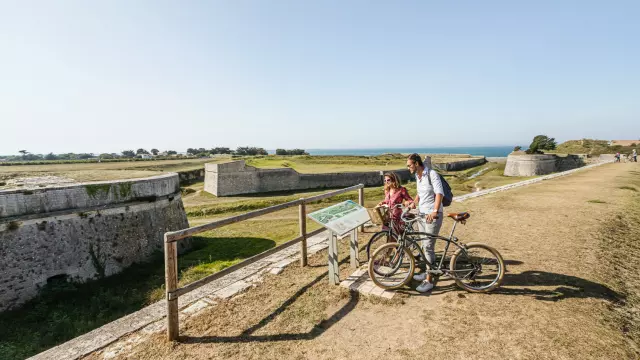 Deux cyclistes s'arrêtent pour lire un panneau d'information sur les fortifications de Saint-Martin.