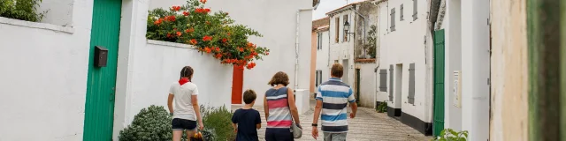 Famille marchant dans une rue avec l’église des Portes-en-Ré.