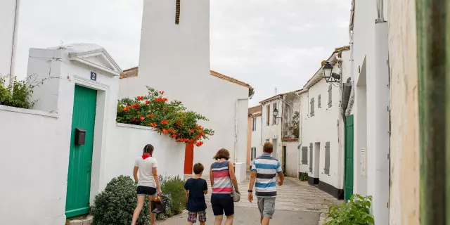 Famille marchant dans une rue avec l’église des Portes-en-Ré.