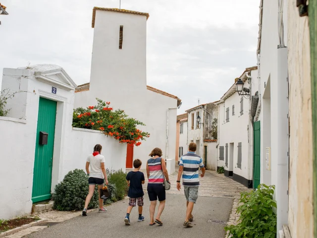 Famille marchant dans une rue avec l’église des Portes-en-Ré.