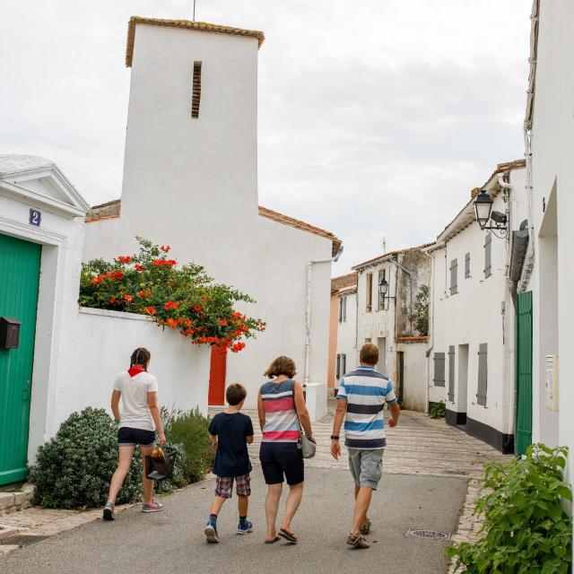 Famille marchant dans une rue avec l’église des Portes-en-Ré.