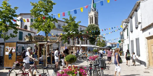 Scène animée d'un marché à La Couarde-sur-Mer avec des vélos et des piétons.