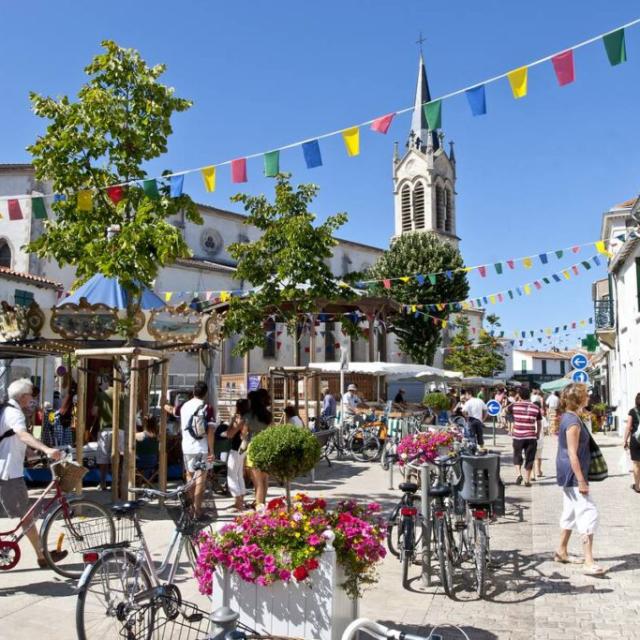 Scène animée d'un marché à La Couarde-sur-Mer avec des vélos et des piétons.