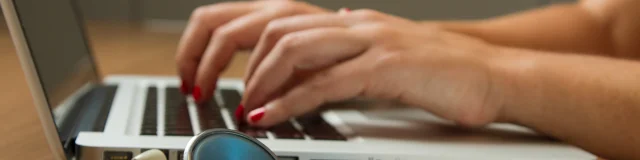 Mains d'un professionnel de santé tapant sur le clavier d'un ordinateur portable avec un stéthoscope.