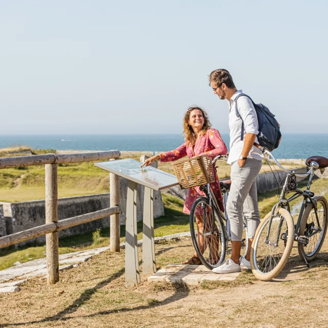 Couple de cycliste enDeux cyclistes s'arrêtent pour lire un panneau d'information sur les fortifications de Saint-Martin.