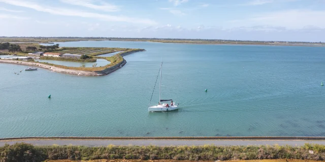 Bateau naviguant sur une mer calme avec un paysage côtier en arrière-plan