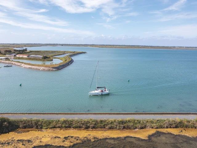 Bateau naviguant sur une mer calme avec un paysage côtier en arrière-plan