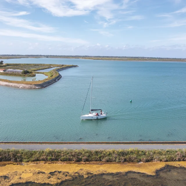 Bateau naviguant sur une mer calme avec un paysage côtier en arrière-plan