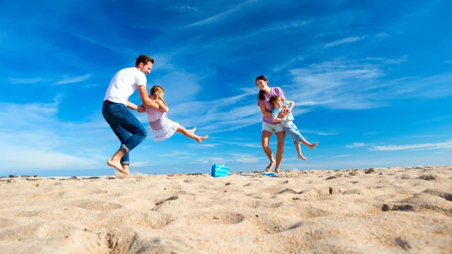 Padres columpiando a sus hijos en la playa