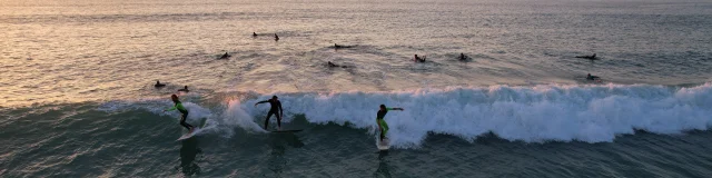 Groupe de surfeurs sur une vague à la plage du Petit Bec