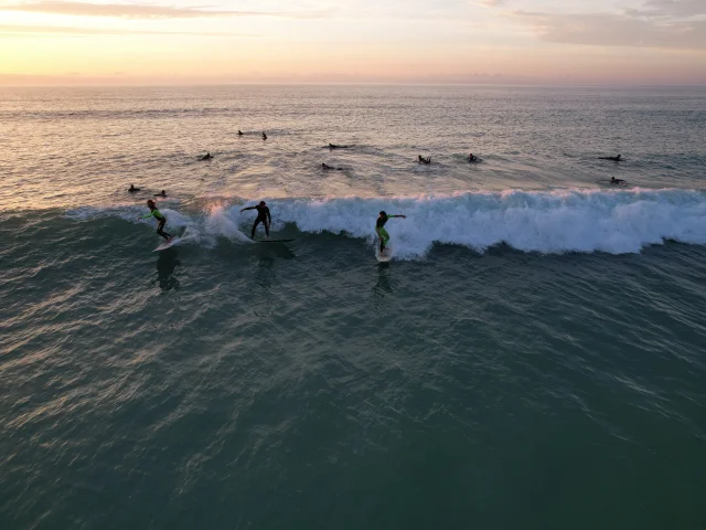 Groupe de surfeurs sur une vague à la plage du Petit Bec