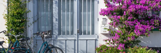 Façade de maison fleurie à La Flotte avec des vélos devant la porte.