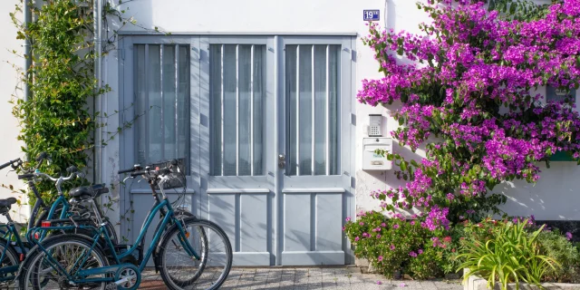 Façade de maison fleurie à La Flotte avec des vélos devant la porte.