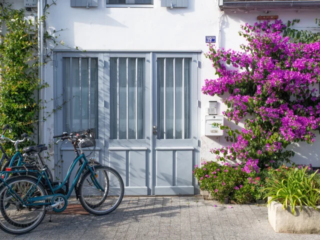 Façade de maison fleurie à La Flotte avec des vélos devant la porte.