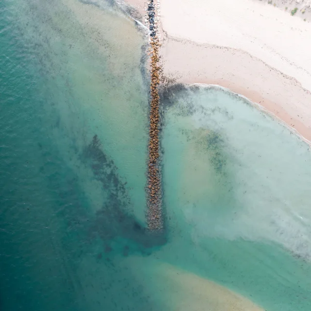 Vue aérienne d'une plage avec une digue de rochers.