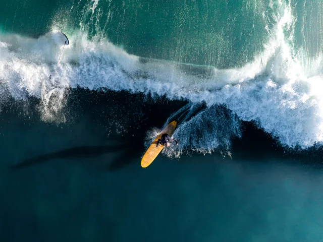 Surfeur capturé en action sur une grande vague vue de haut.