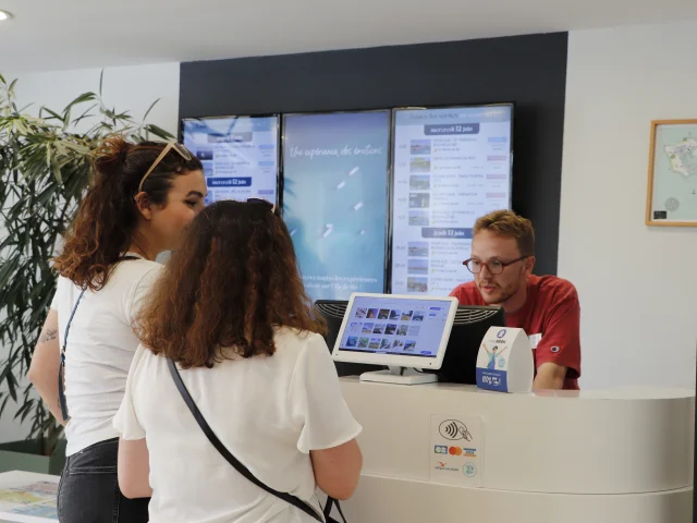 Deux visiteurs discutant avec un employé au bureau d'information de Saint-Martin.