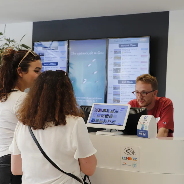 Deux visiteurs discutant avec un employé au bureau d'information de Saint-Martin.