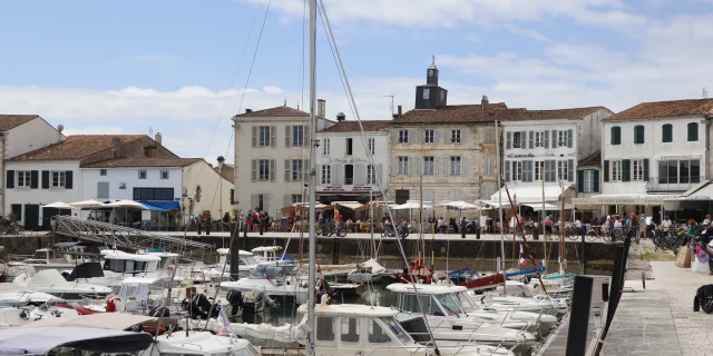 Vue du port de La Flotte avec des bateaux amarrés et des bâtiments en arrière-plan.