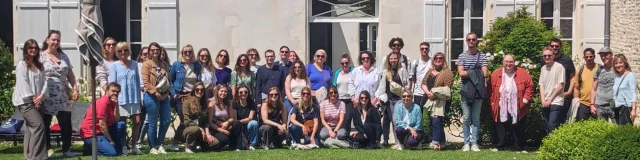 Groupe de personnes posant devant un bâtiment historique, formant l'équipe de l'office de tourisme.