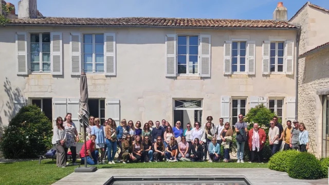 Groupe de personnes posant devant un bâtiment historique, formant l'équipe de l'office de tourisme.