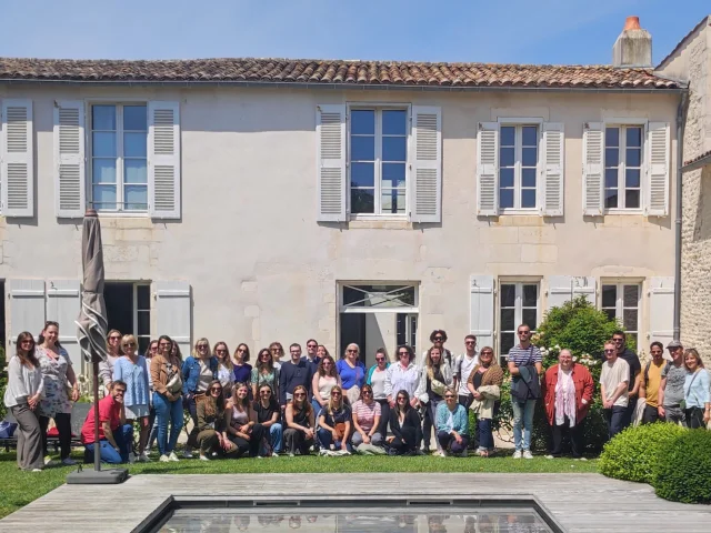 Groupe de personnes posant devant un bâtiment historique, formant l'équipe de l'office de tourisme.