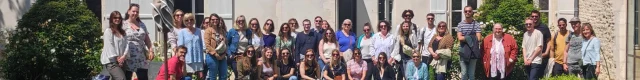 Groupe de personnes posant devant un bâtiment historique, formant l'équipe de l'office de tourisme.