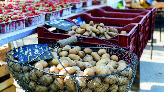 Marché avec des étals de pommes de terre et de fraises.