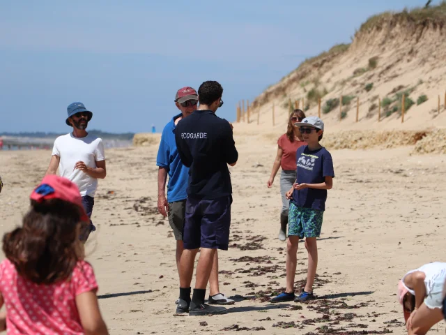 Groupe de personnes en excursion éducative sur une plage.