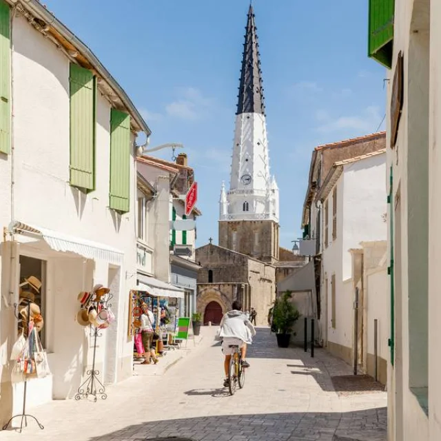 Vue sur l'église d'Ars-en-Ré au bout d'une rue animée de l'île de Ré.