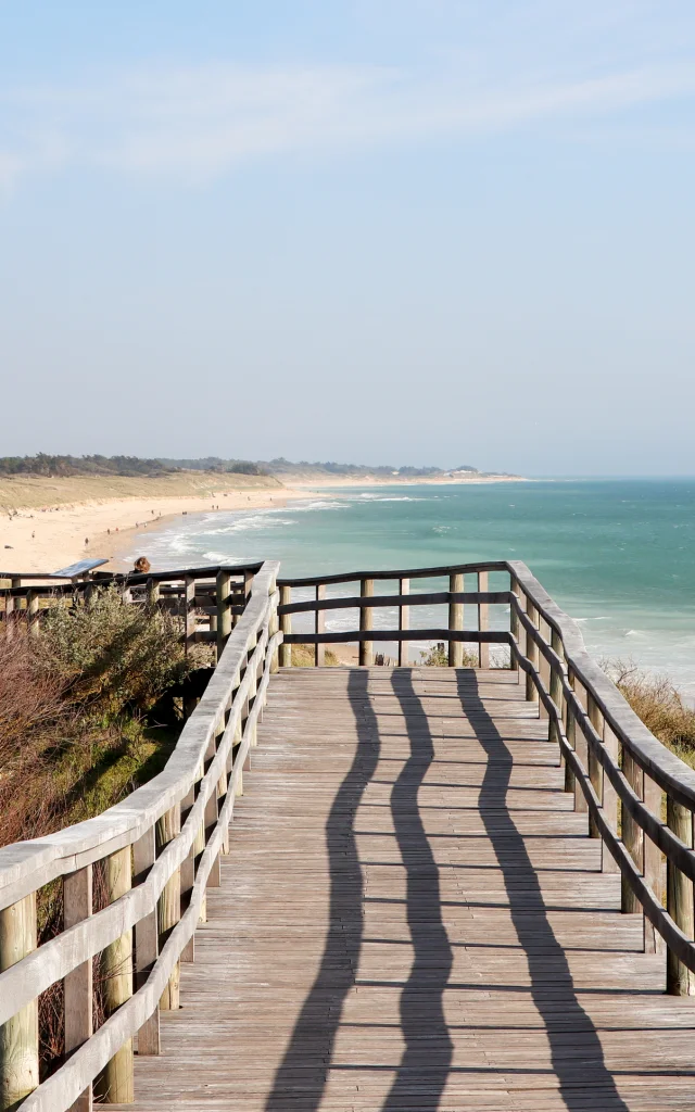 Estacade en bois menant à la plage avec vue sur l'océan.