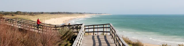 Estacade en bois menant à la plage avec vue sur l'océan.