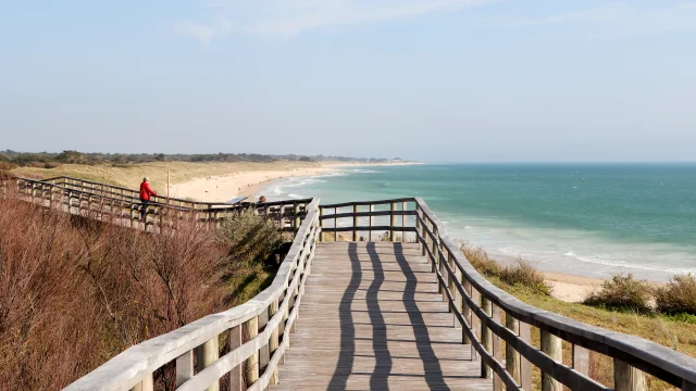 Estacade en bois menant à la plage avec vue sur l'océan.