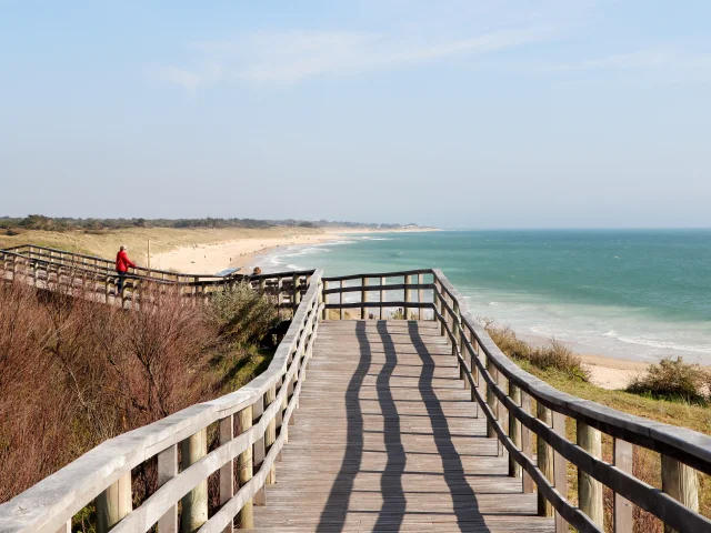 Estacade en bois menant à la plage avec vue sur l'océan.