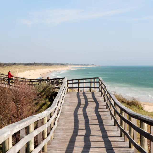 Estacade en bois menant à la plage avec vue sur l'océan.