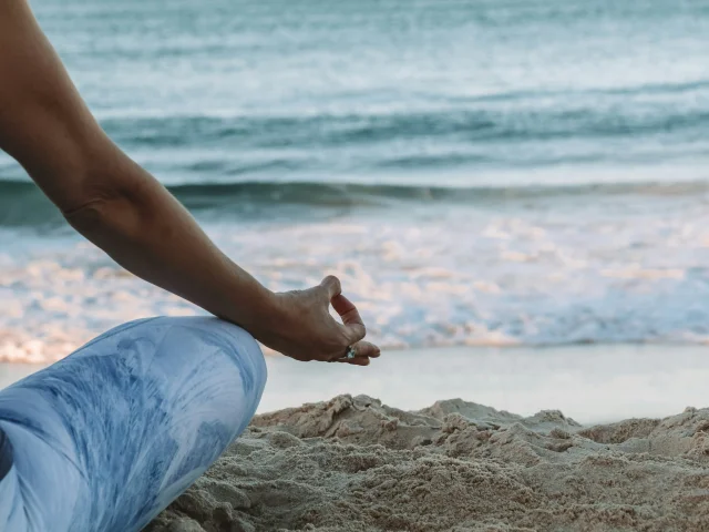 Femme pratiquant le yoga sur la plage.