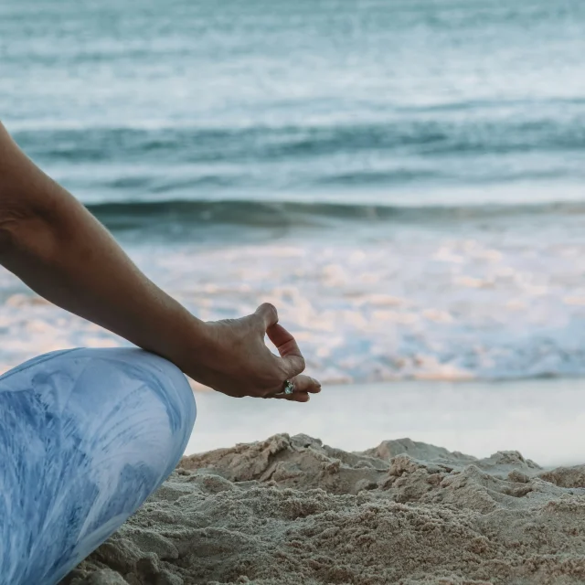 Femme pratiquant le yoga sur la plage.