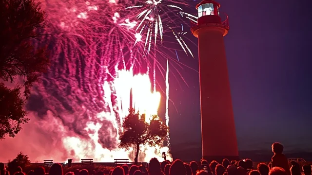 Spectacle de feu d'artifice avec un phare en arrière-plan.