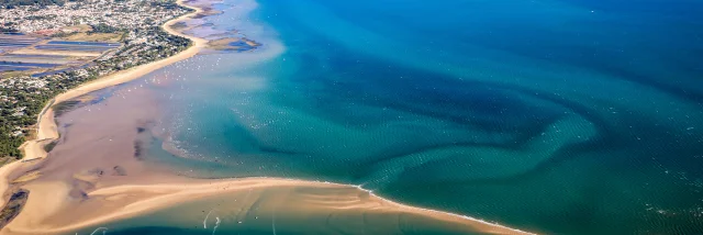 Vue aérienne de l'île de Ré montrant ses plages, eaux turquoise et villages côtiers.