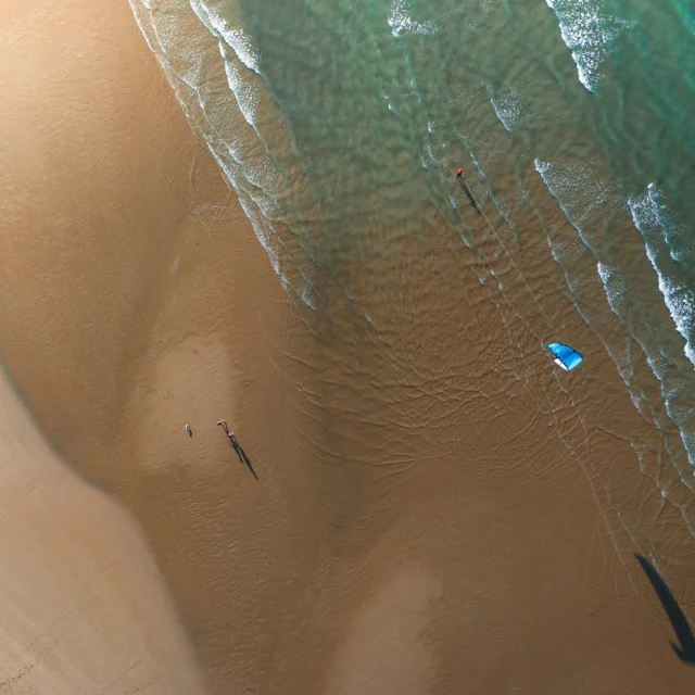 Vue aérienne d'une plage avec un kite surfeur et des vagues.