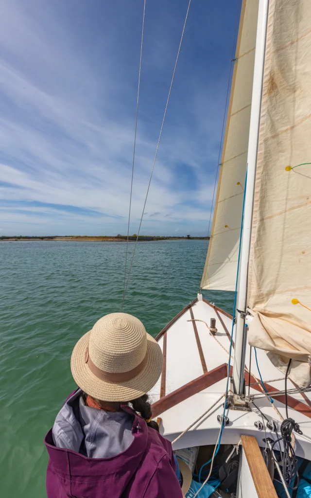 Une femme portant un chapeau regardant la mer depuis un bateau à l'île de Ré