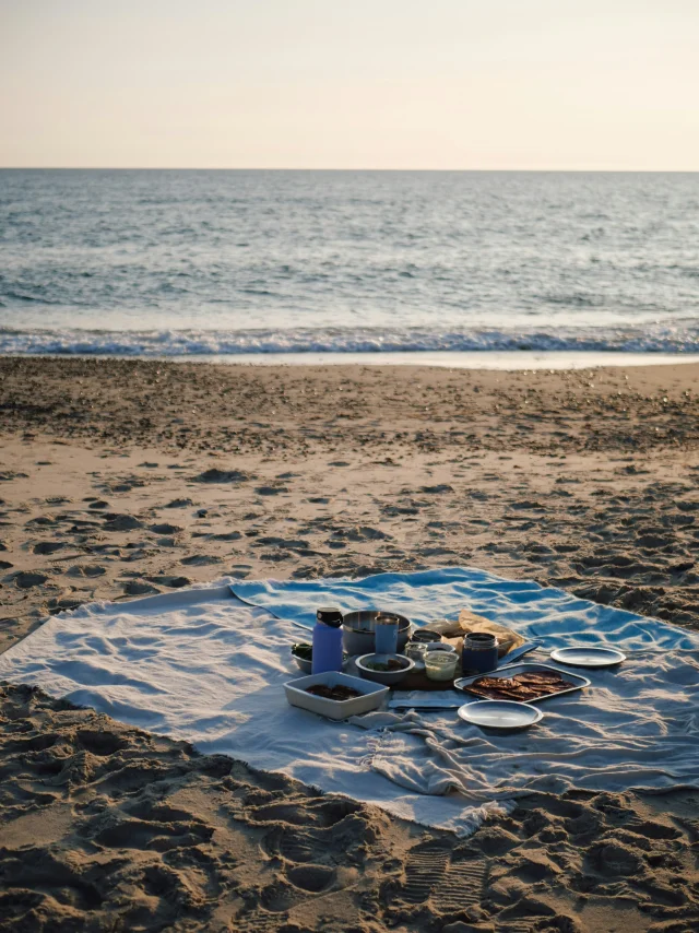 Pique-nique en bord de plage, face au coucher de soleil sur la mer