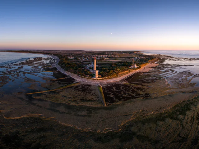 Vue aérienne du phare des Baleines sur la côte avec des marais au coucher du soleil.