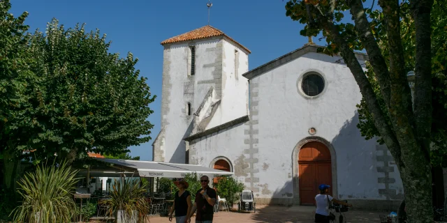 Personnes devant l'église de Loix avec des arbres autour.