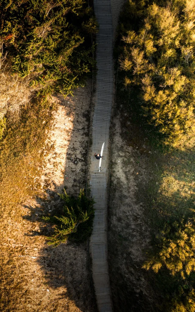 Vue aérienne d'un chemin dans les dunes avec un surfeur