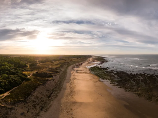 Une plage déserte au crépuscule avec des nuages et des vagues douces.