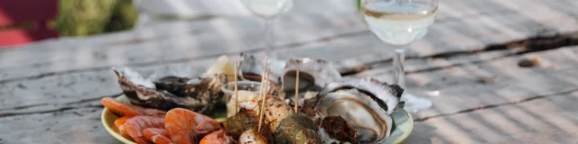 Un plateau de fruits de mer avec des verres de vin sur une table en bois.