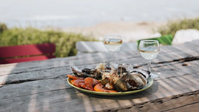 Un plateau de fruits de mer avec des verres de vin sur une table en bois.